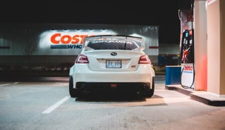 Contemporary white car parked near pump on fuel station at night in city